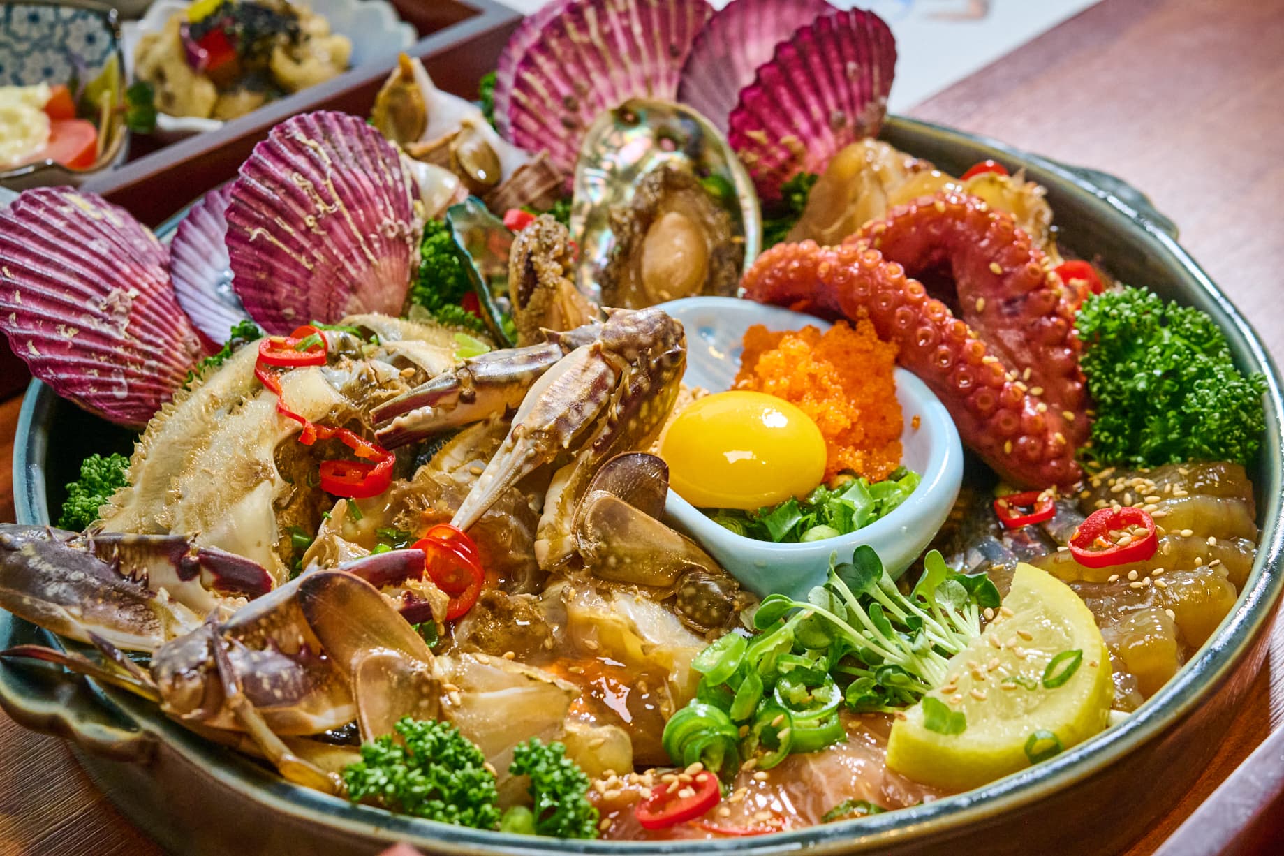 꽃게, 전복, 문어, 가리비가 담긴 해물장 한 접시와 가운데 올린 노른자